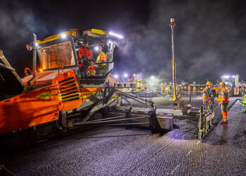 A paver equipped with two TrimbleMT900 Machine Targets begins laying asphalt, to the left of the axis of the runway - Photo La Compagnie Générale de Photographie